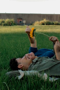 A couple enjoying a serene moment with a sunflower, lying on grass in Buenos Aires.