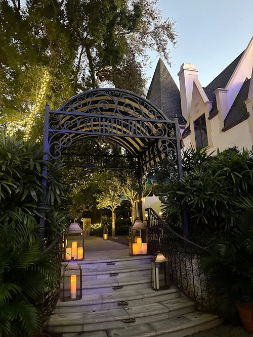 Free A beautifully lit pathway with an ornate archway leading to a charming building at twilight. Stock Photo