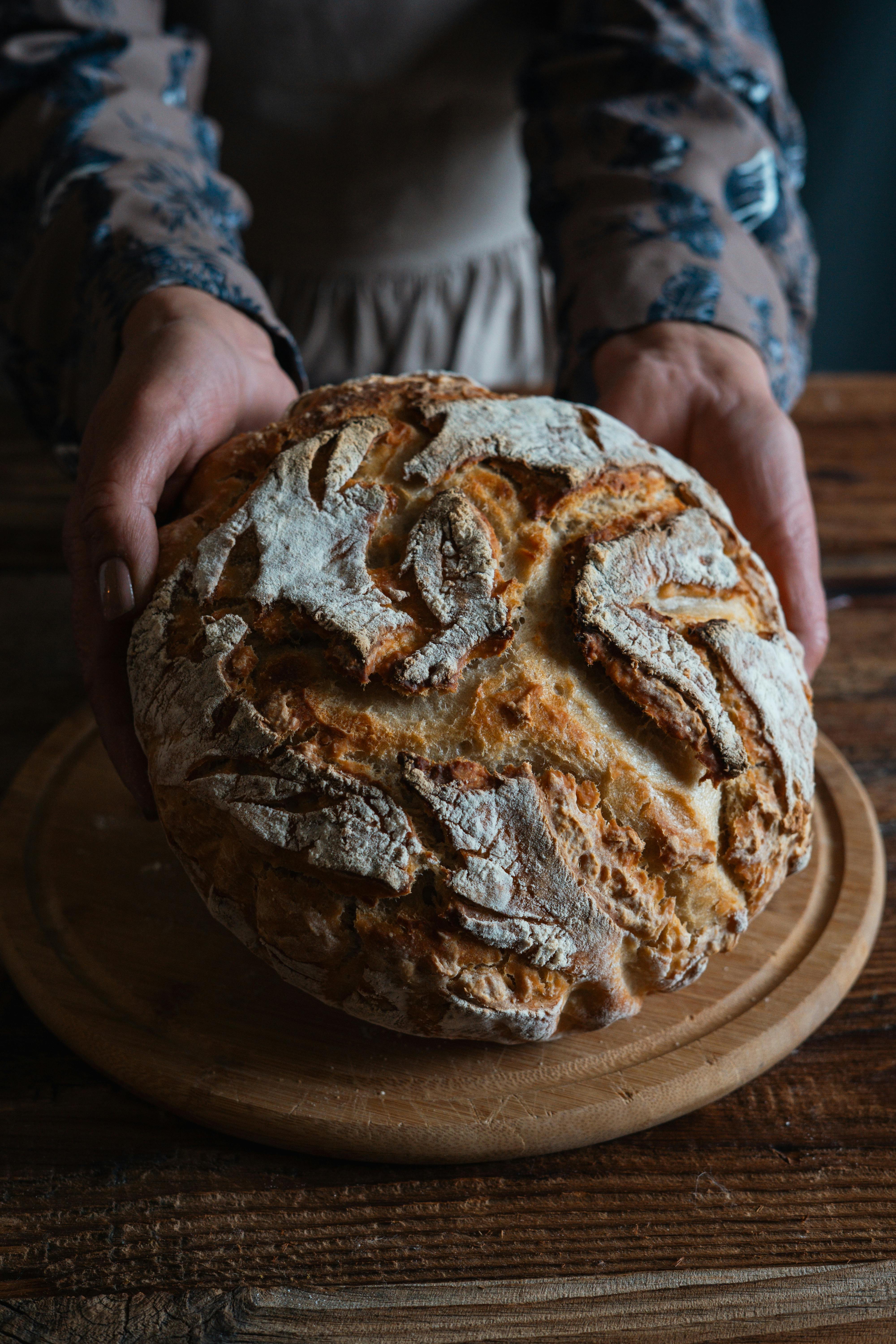 Free A close-up of rustic, freshly baked bread placed on a wooden table, ideal for artisan food themes. Stock Photo