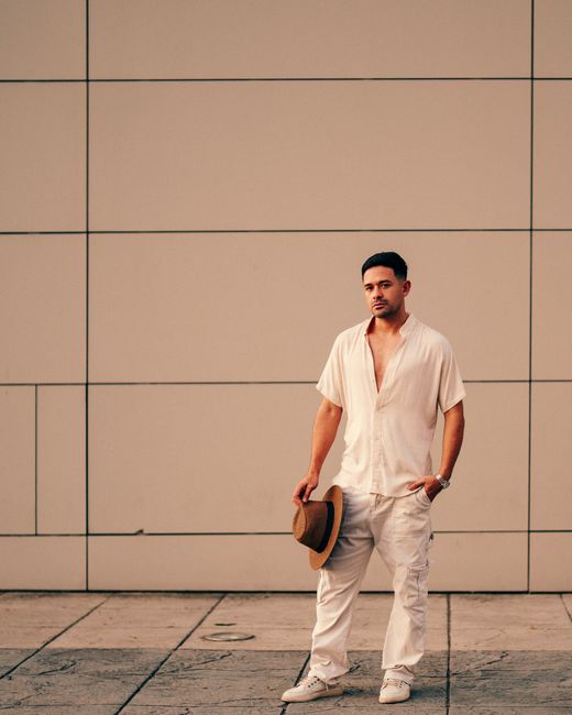 Portrait of a stylish man holding a hat against a modern urban wall in Buenos Aires.