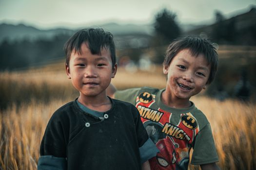 Two smiling children enjoying the outdoors in a golden wheat field during daytime, showcasing happiness and friendship.