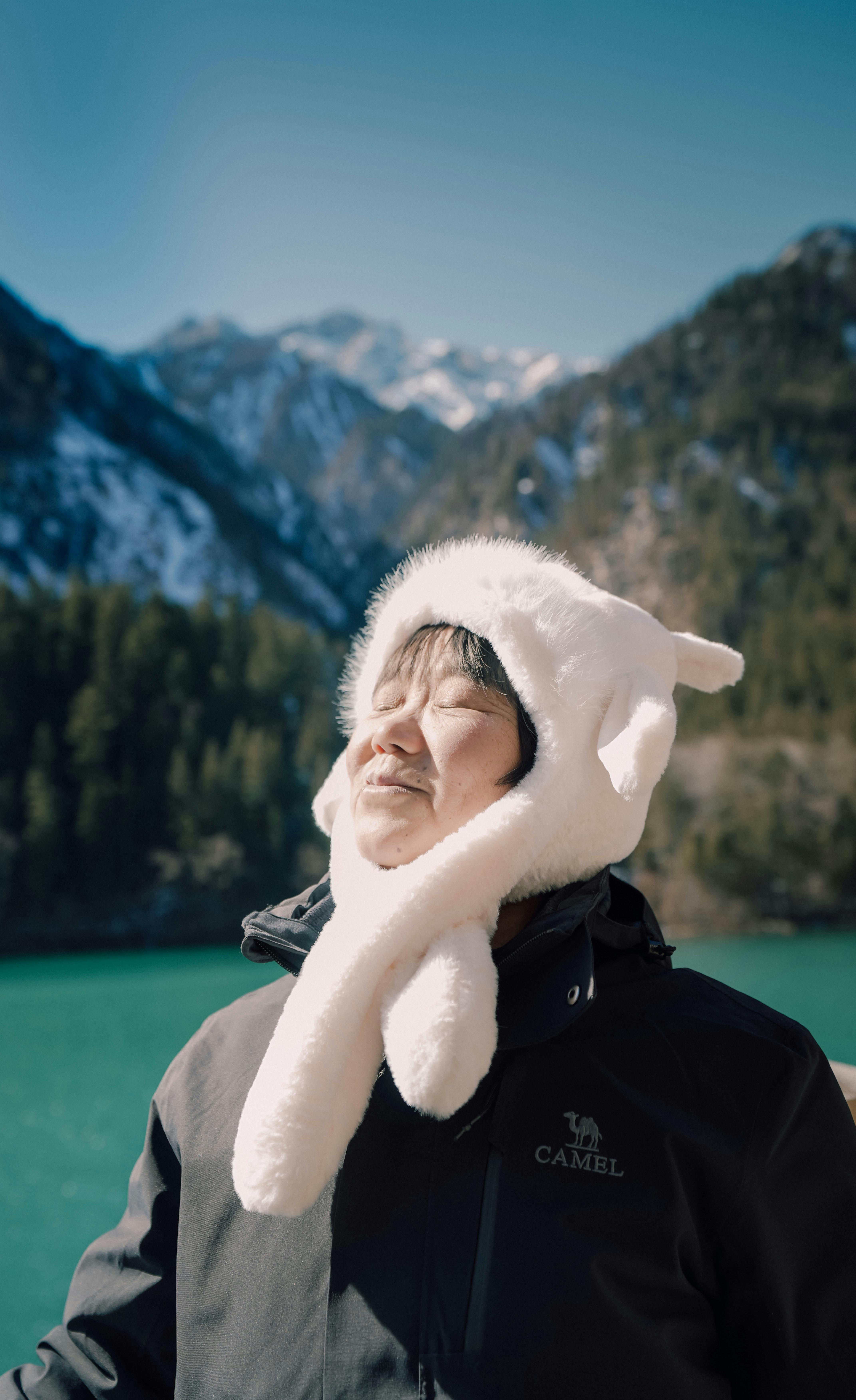 Adult appreciating mountain scenery wearing a cozy hat, capturing serene winter vibes.