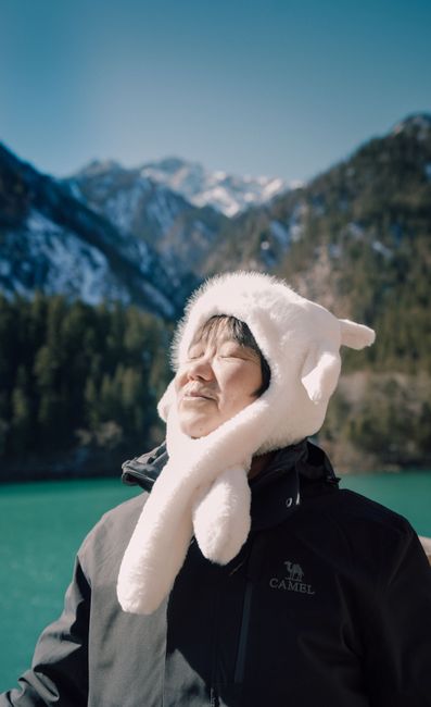 Adult appreciating mountain scenery wearing a cozy hat, capturing serene winter vibes.
