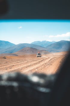 Off-road vehicle traveling through the rugged Uyuni desert landscape in Bolivia.