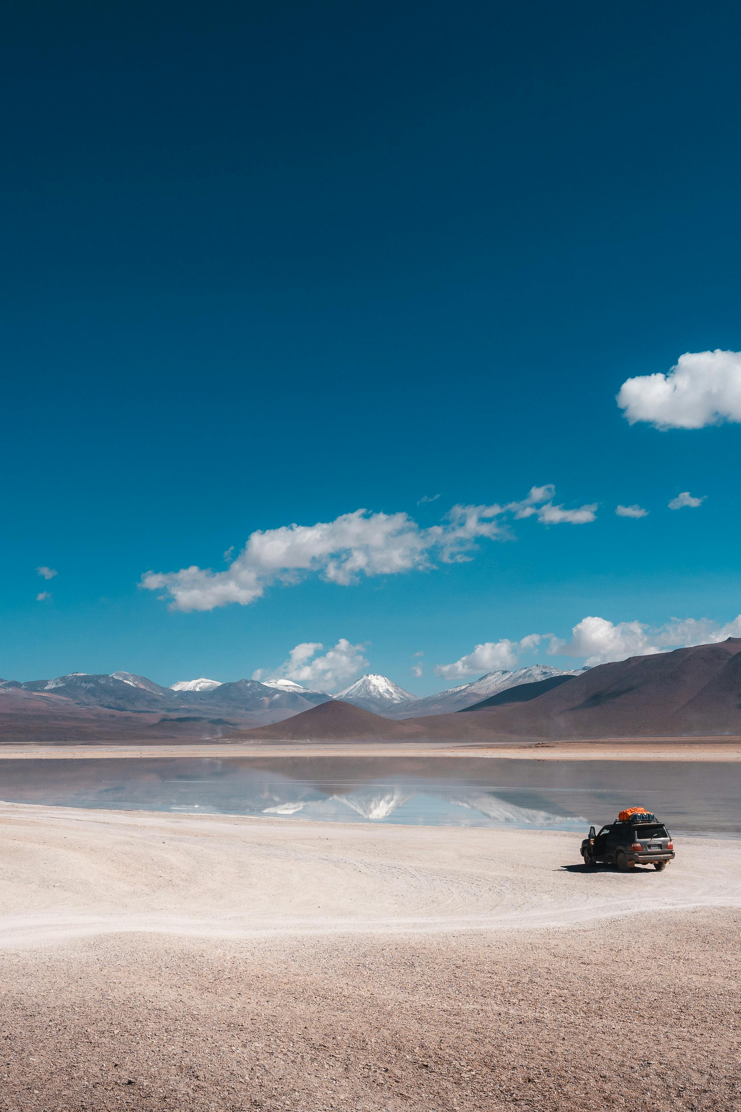 A lone vehicle on Uyuni's reflective salt flats under clear blue skies.