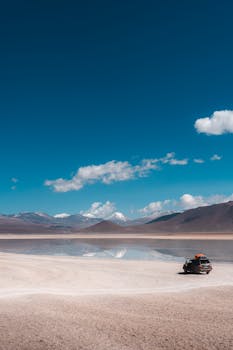 A lone vehicle on Uyuni's reflective salt flats under clear blue skies.