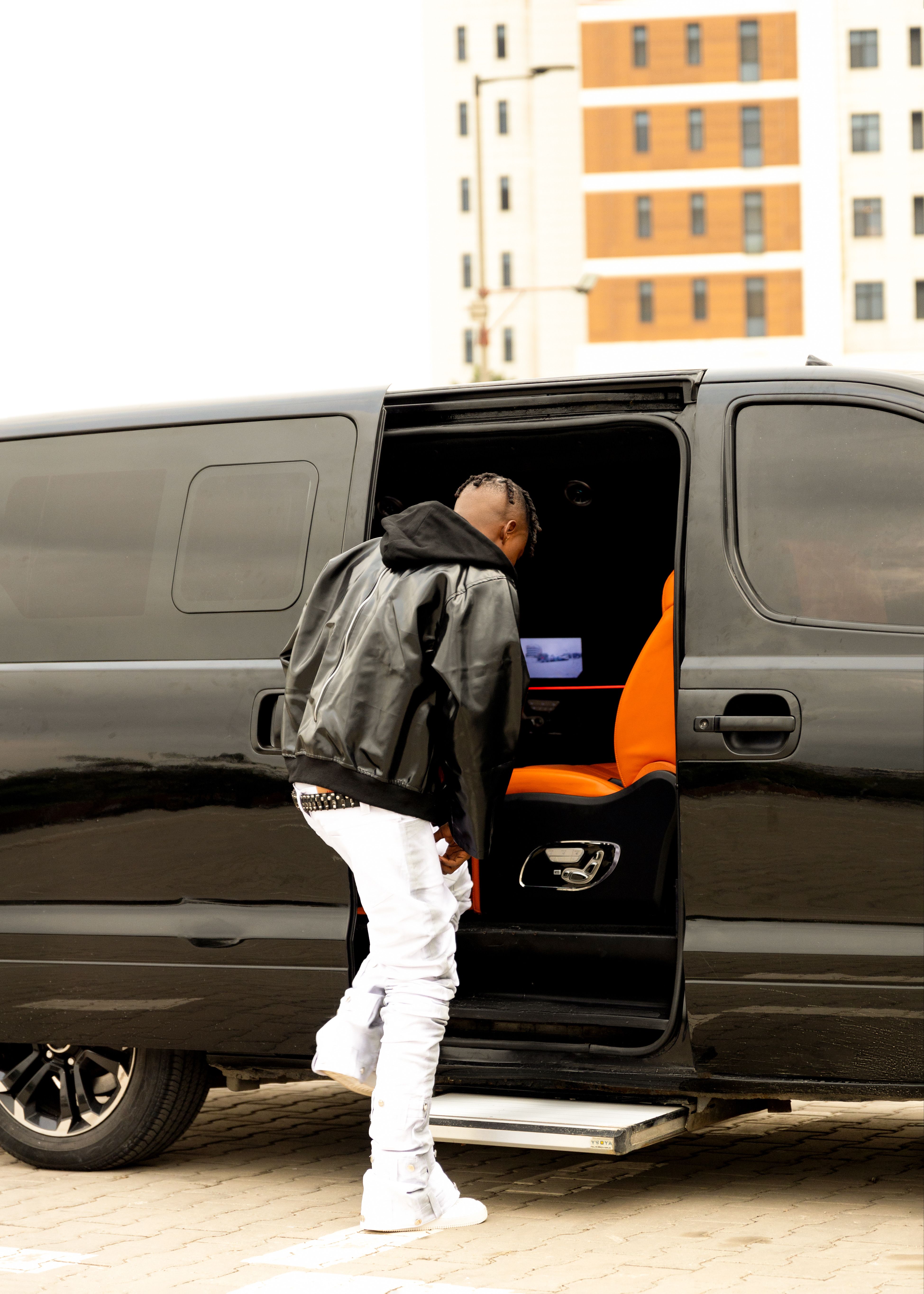 A man in casual attire enters a black van in a city environment.