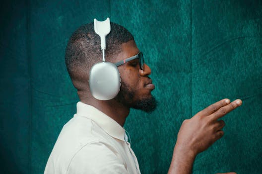 A man wearing stylish headphones and sunglasses in a teal room, capturing modern music vibes.