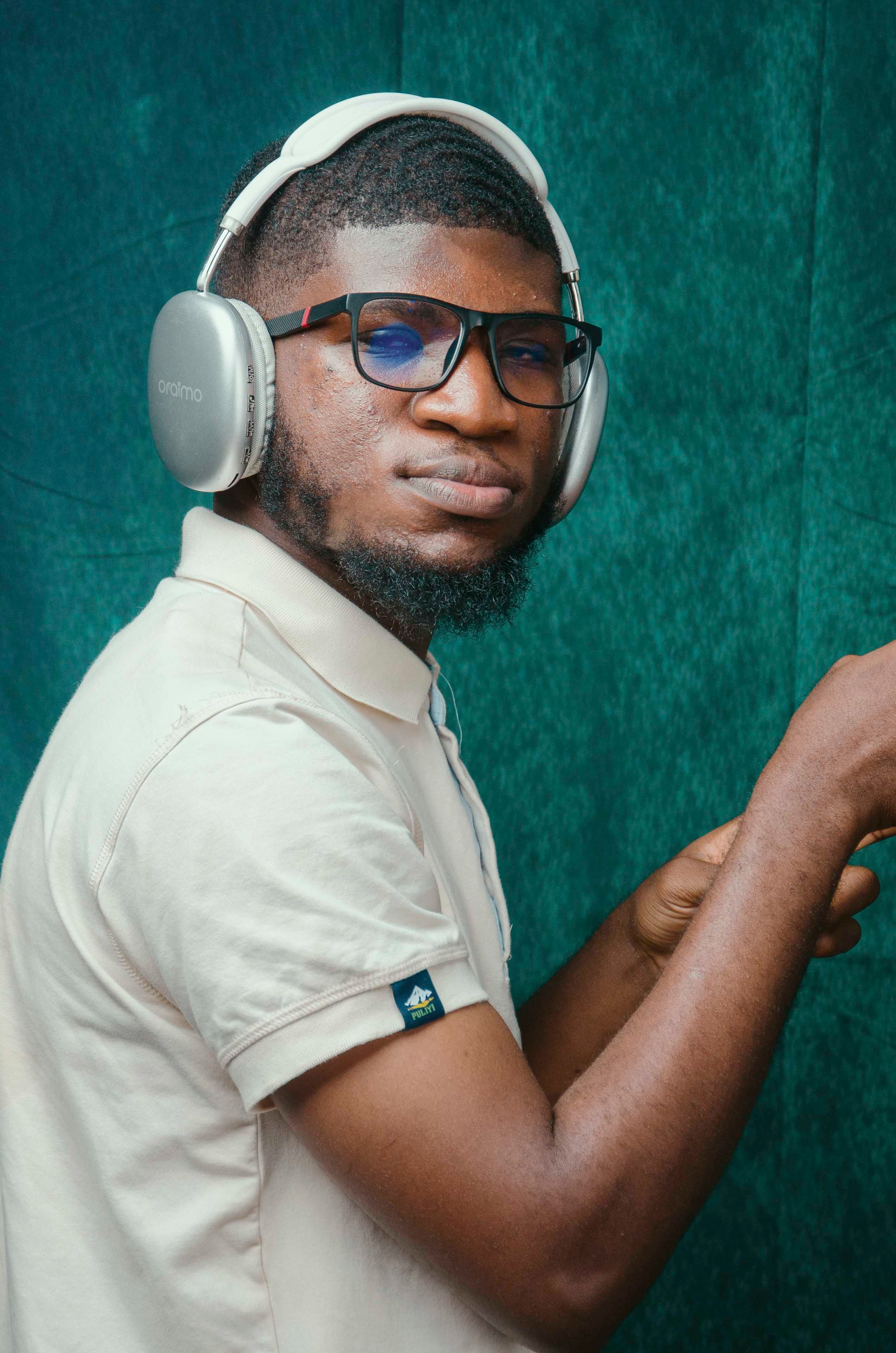 Young man in Accra wearing headphones and glasses. Captured indoors with a vivid background.