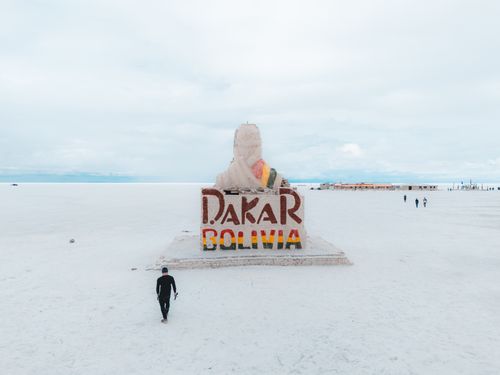 Free A solitary traveler approaches the Dakar Rally Monument in the vast Salar de Uyuni, Bolivia. Stock Photo
