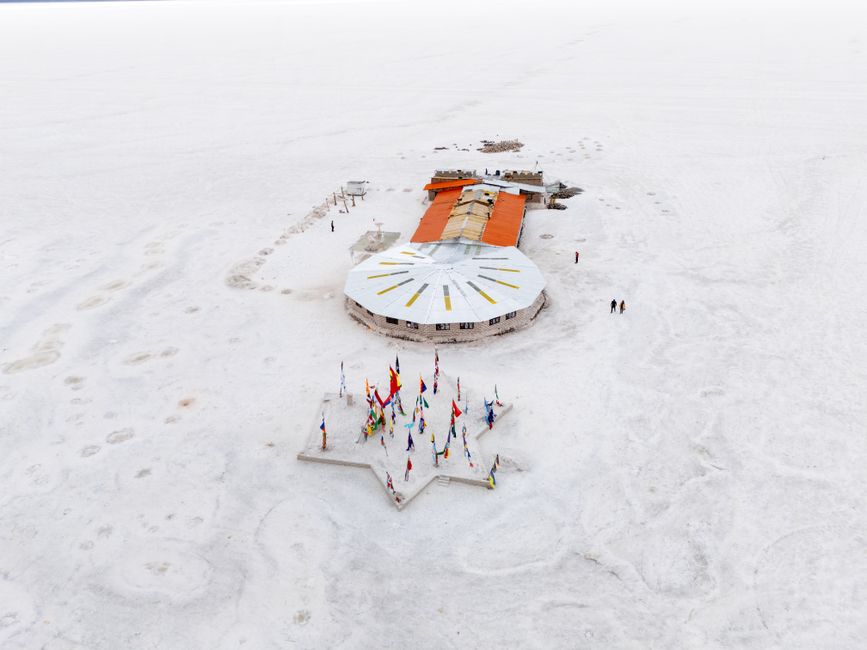 Stunning aerial shot of Uyuni Salt Flats in Bolivia, showcasing flags and unique architecture.