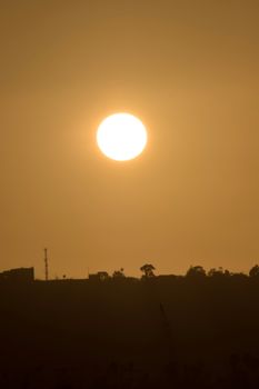 A striking golden sunset over a silhouetted landscape, creating a dramatic scene.
