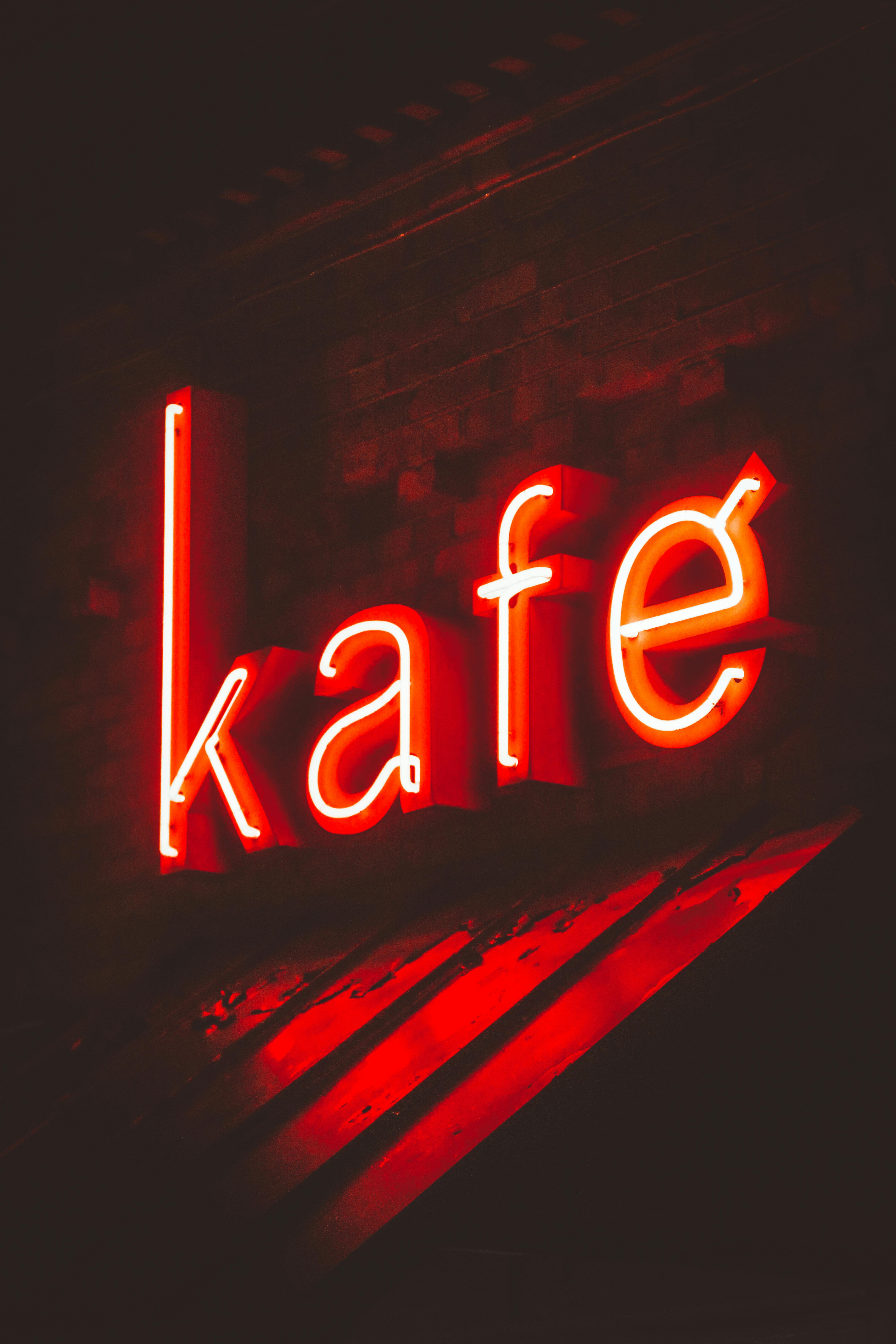 Bright red neon sign displaying 'kafe' at night, adding vibrant urban charm.