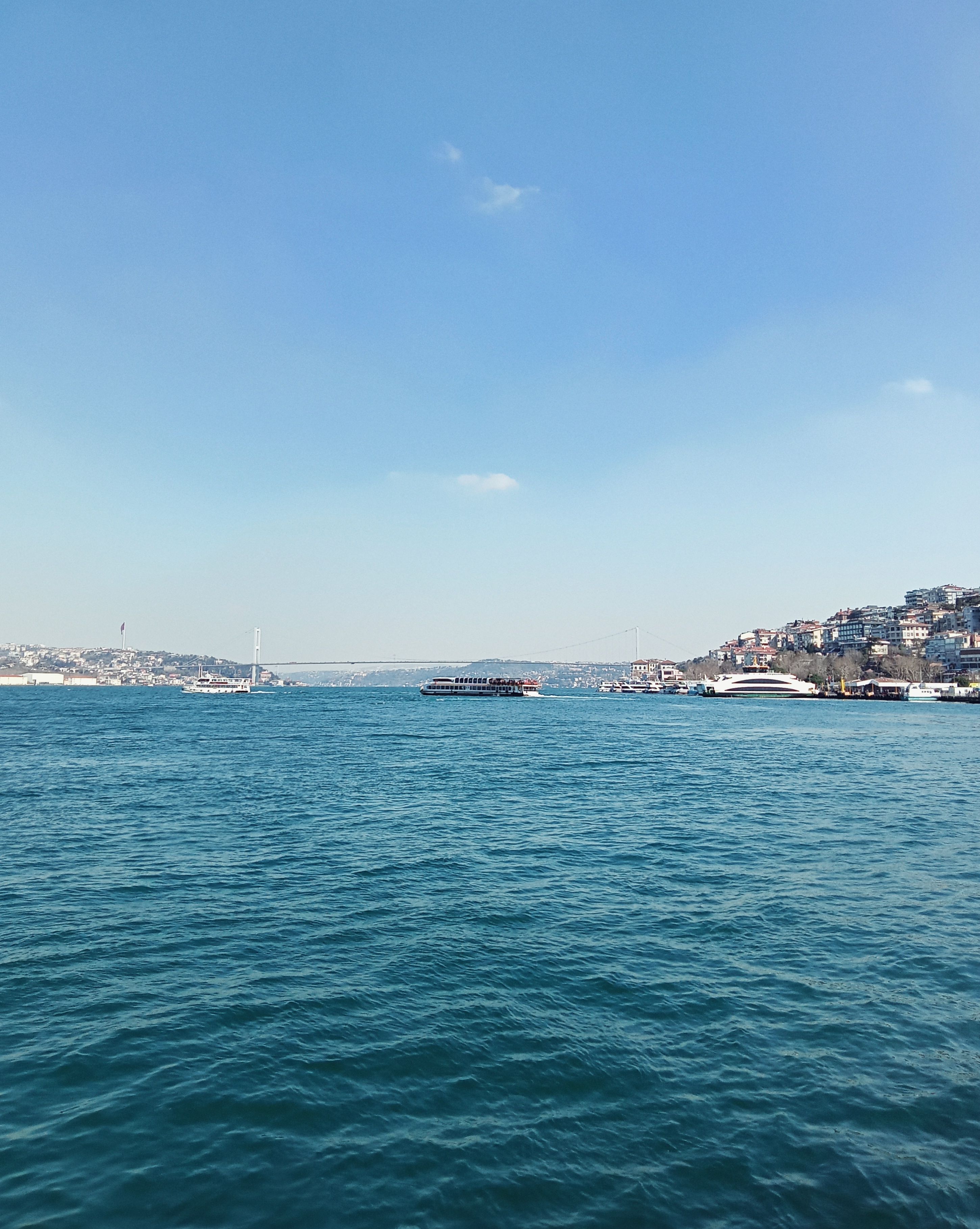 Picturesque Bosphorus view in İstanbul featuring a ferry and the iconic bridge.