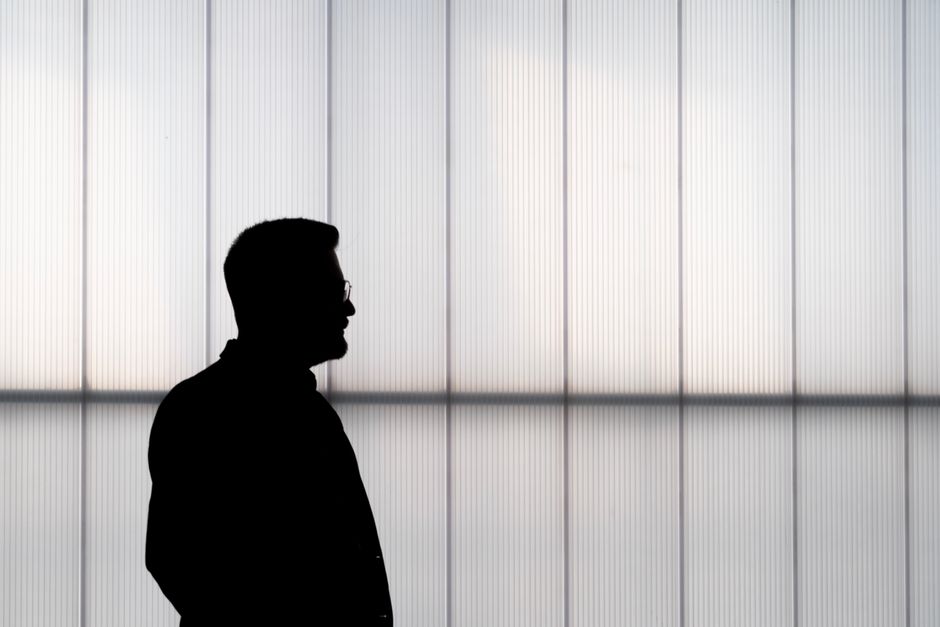 Silhouette of a man in profile against a minimalist geometric background wall.