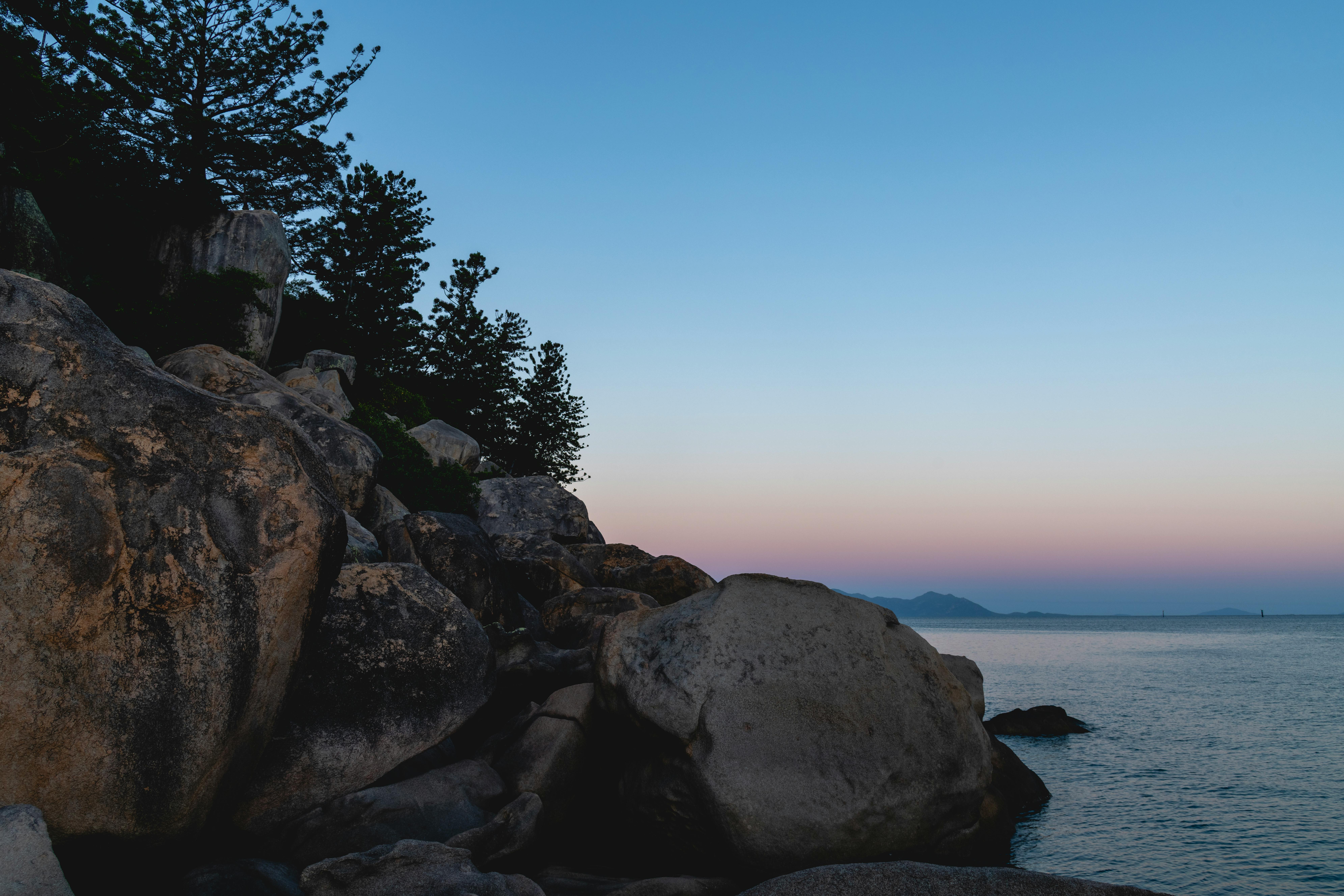 rocky shoreline at twilight with calm waters