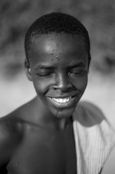 Emotive black and white portrait of a smiling young boy taken outdoors. - Fotografer Sidoarjo