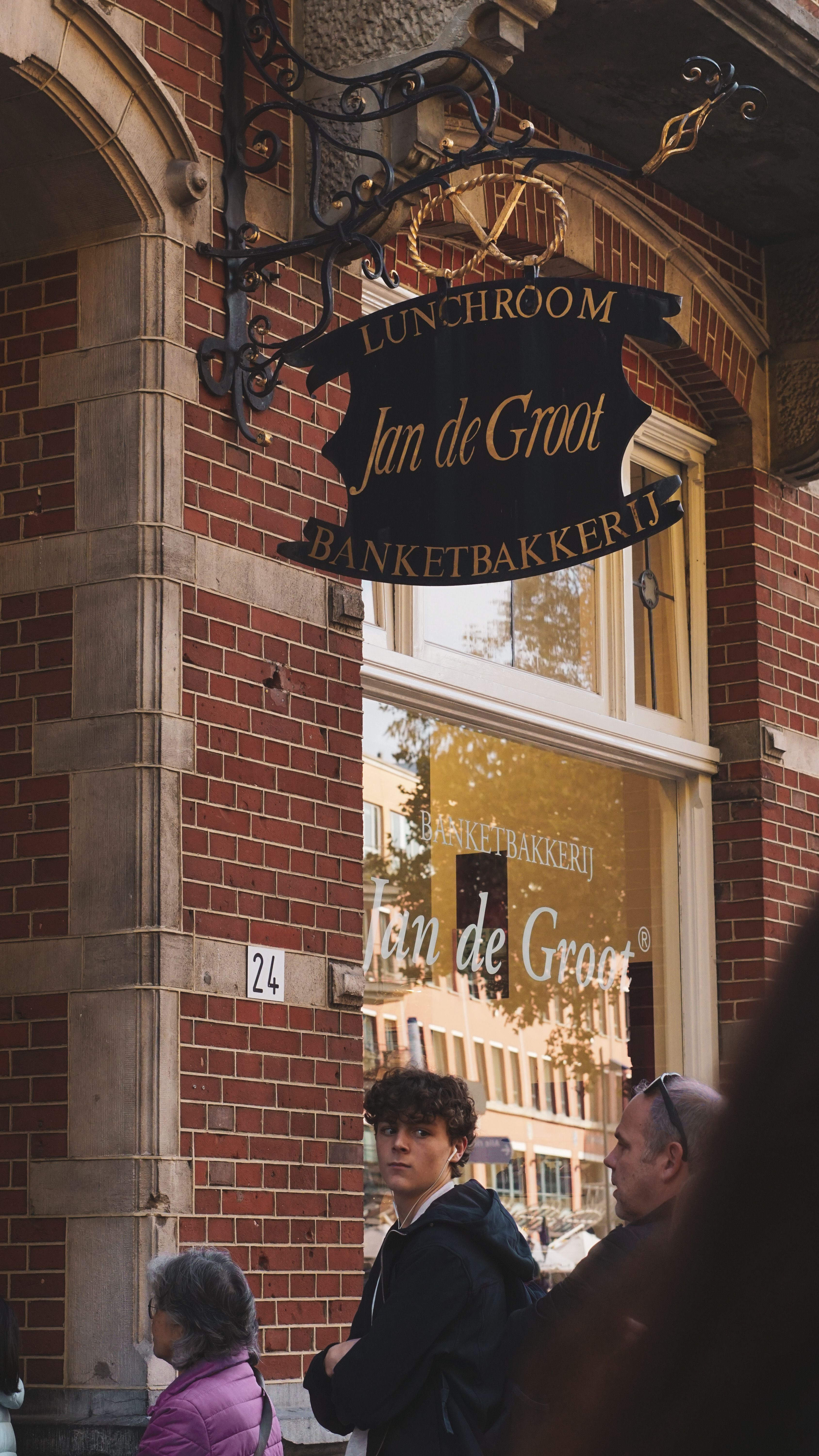 People outside Jan de Groot lunchroom, showcasing historic architectural style.
