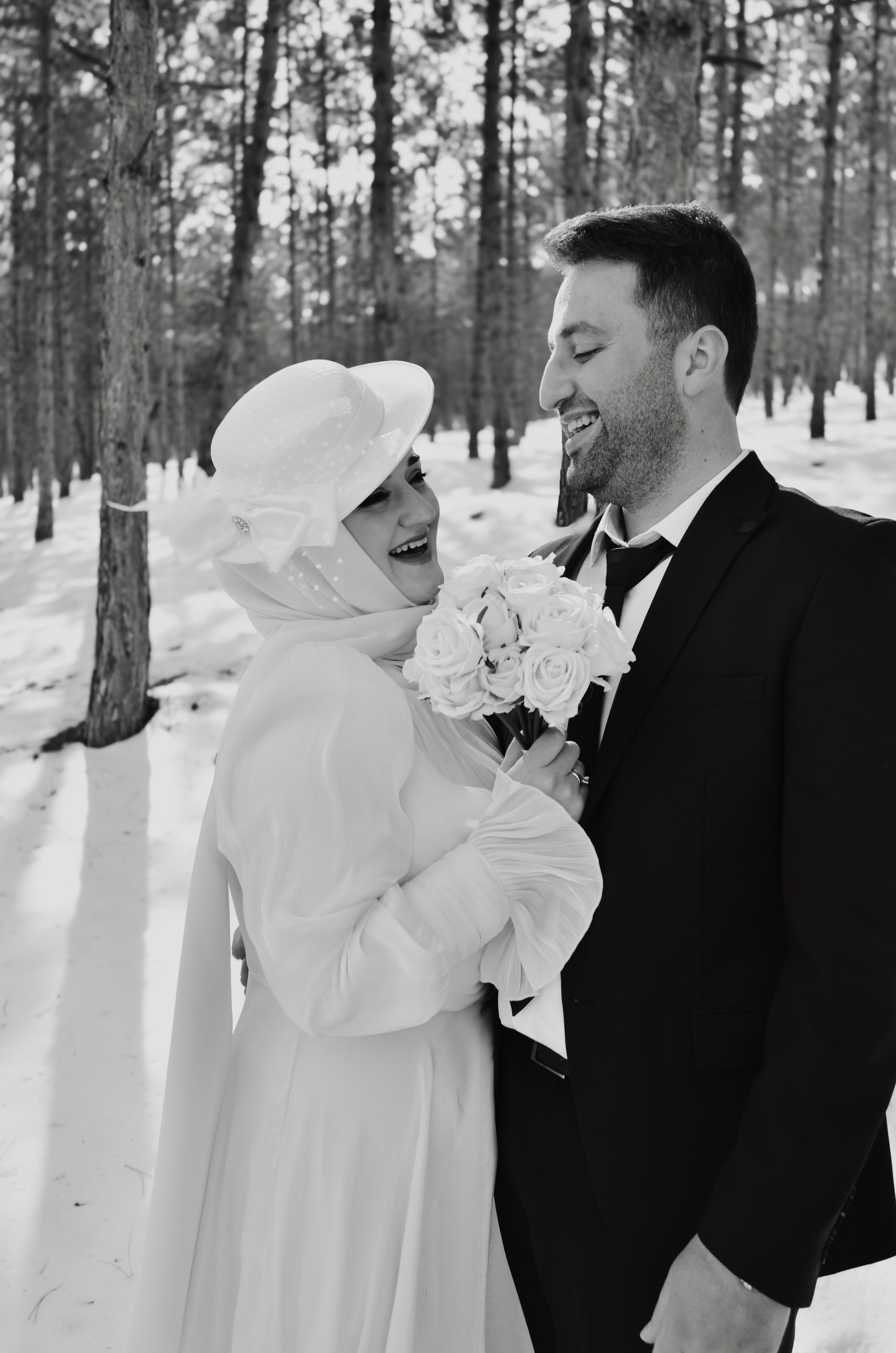 Bride and groom smiling in a snowy forest setting, capturing love and elegance.