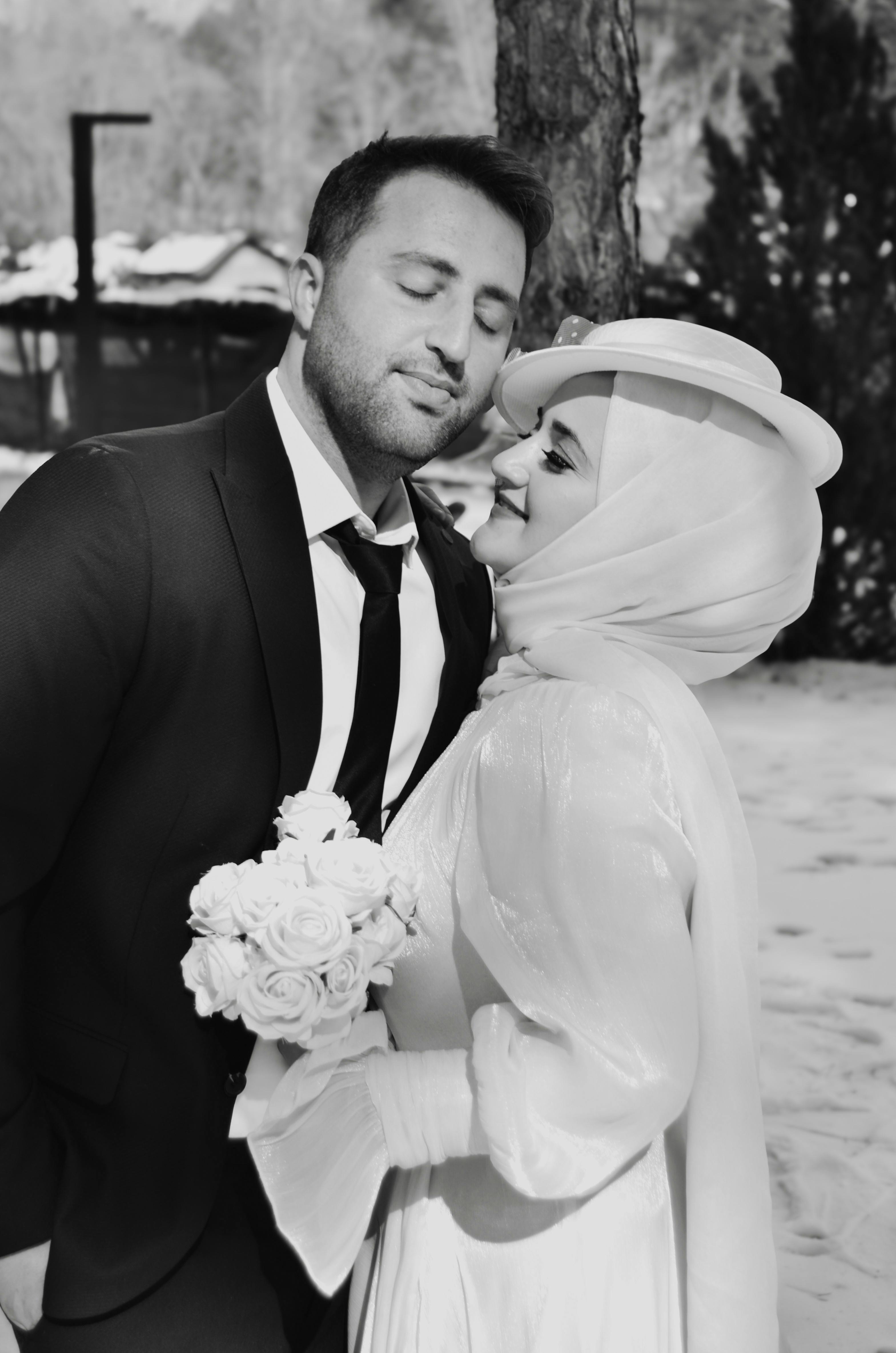 A couple in elegant attire sharing a moment in a snowy outdoor winter setting.