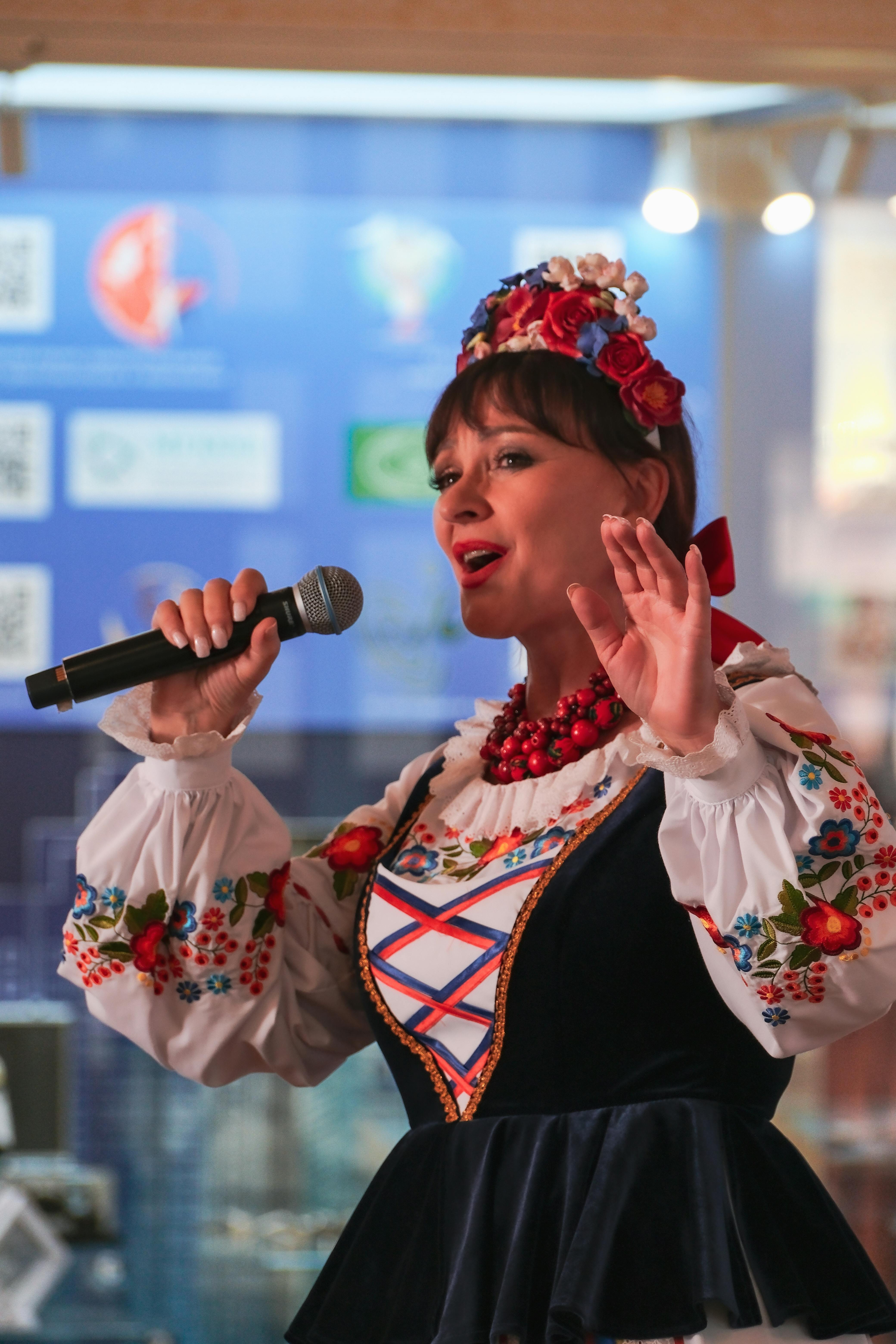 Woman performing in traditional Russian attire with microphone indoors.