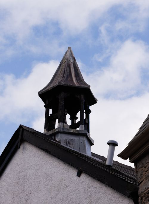 Free A weathered wooden steeple crowns the rooftop against a bright blue sky. Stock Photo