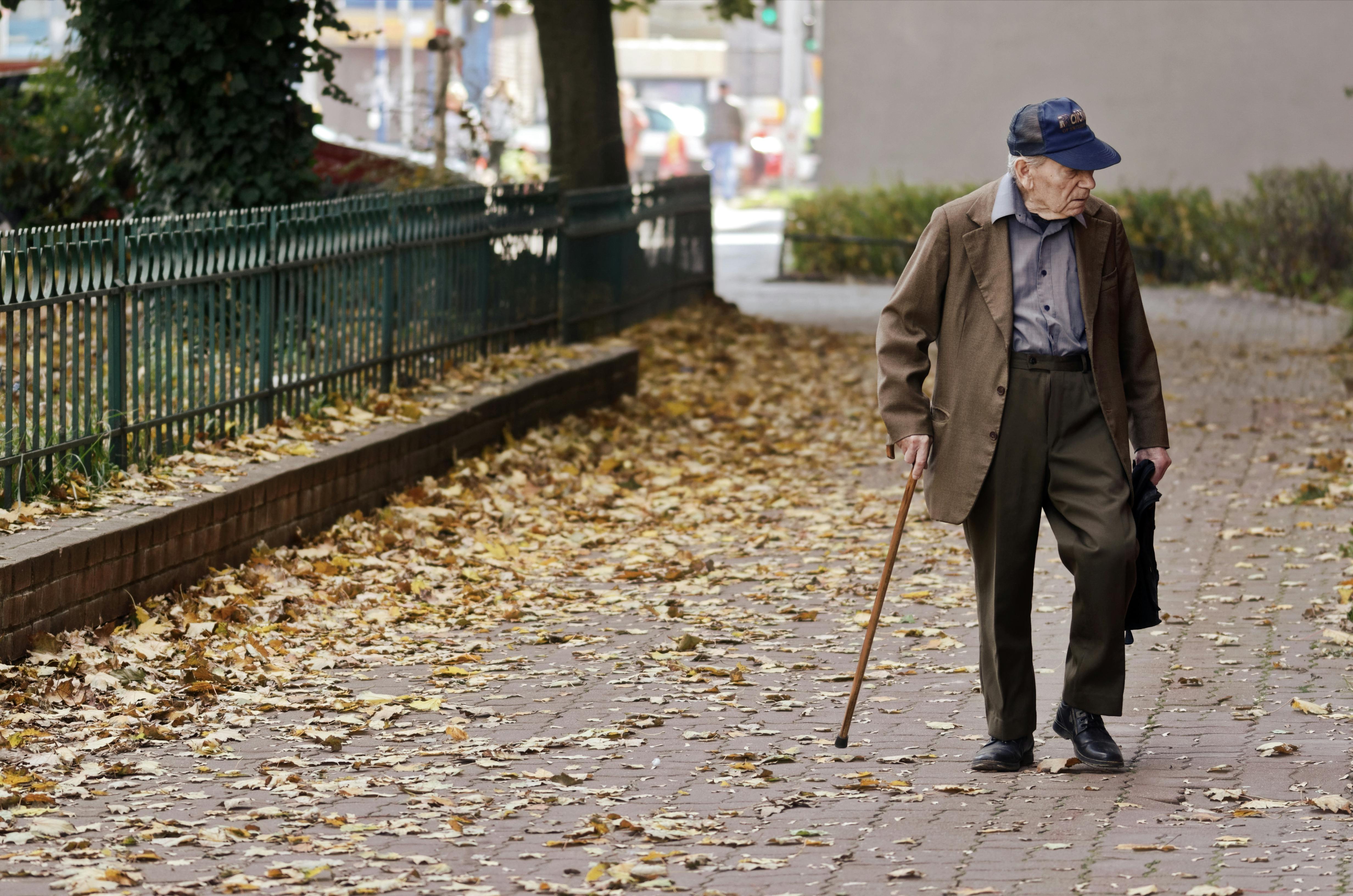 Elderly man walking on pavement. | Photo: Pexels