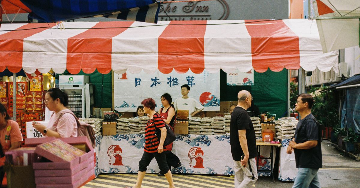 Crowd of diverse people leaving a large modern church in Singapore, street food stalls in background