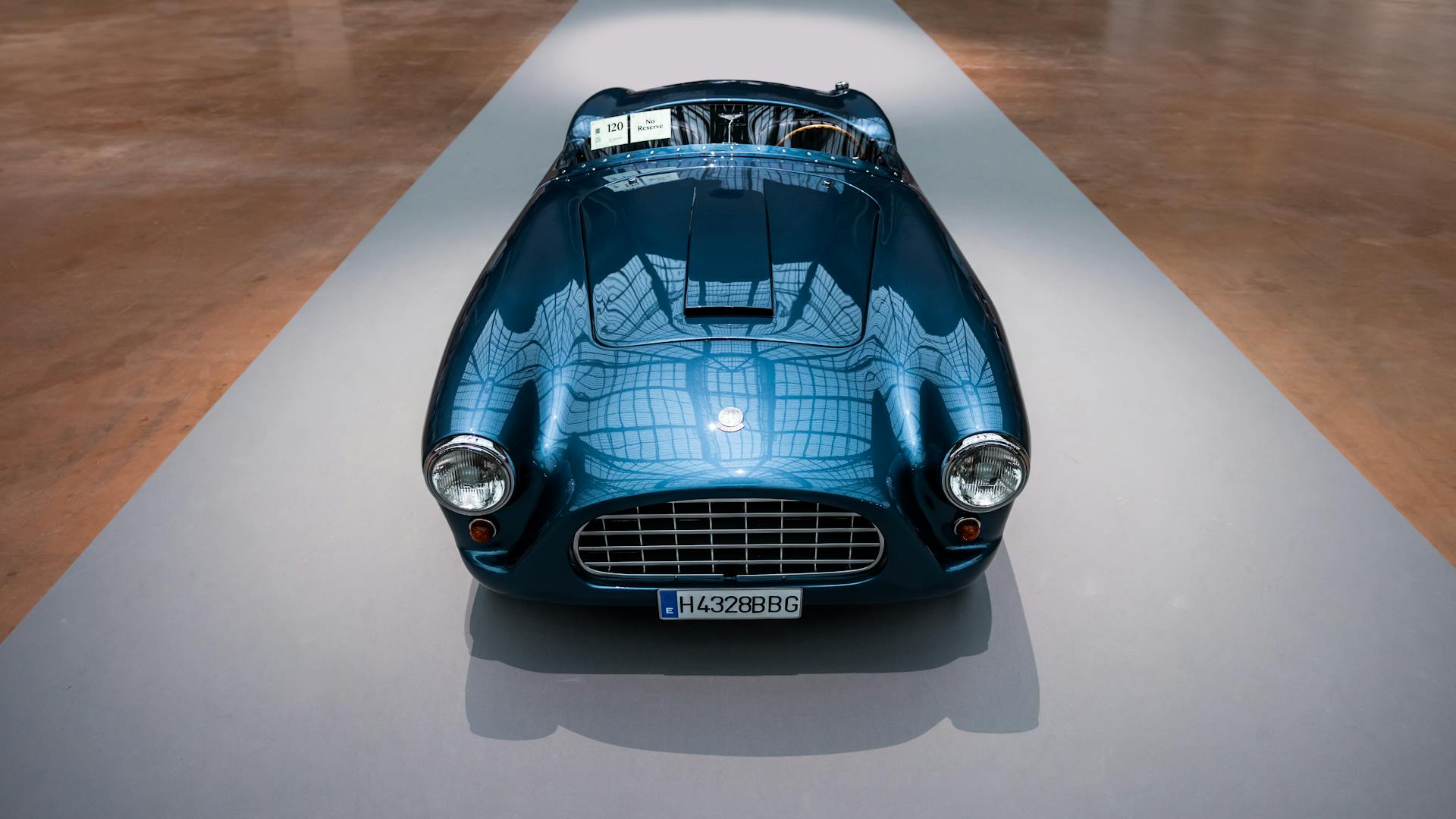 Front view of a polished blue vintage car on display indoors, showcasing classic design.