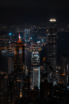 Stunning aerial view of Hong Kong skyline at night, showcasing iconic skyscrapers illuminated against a dark sky.