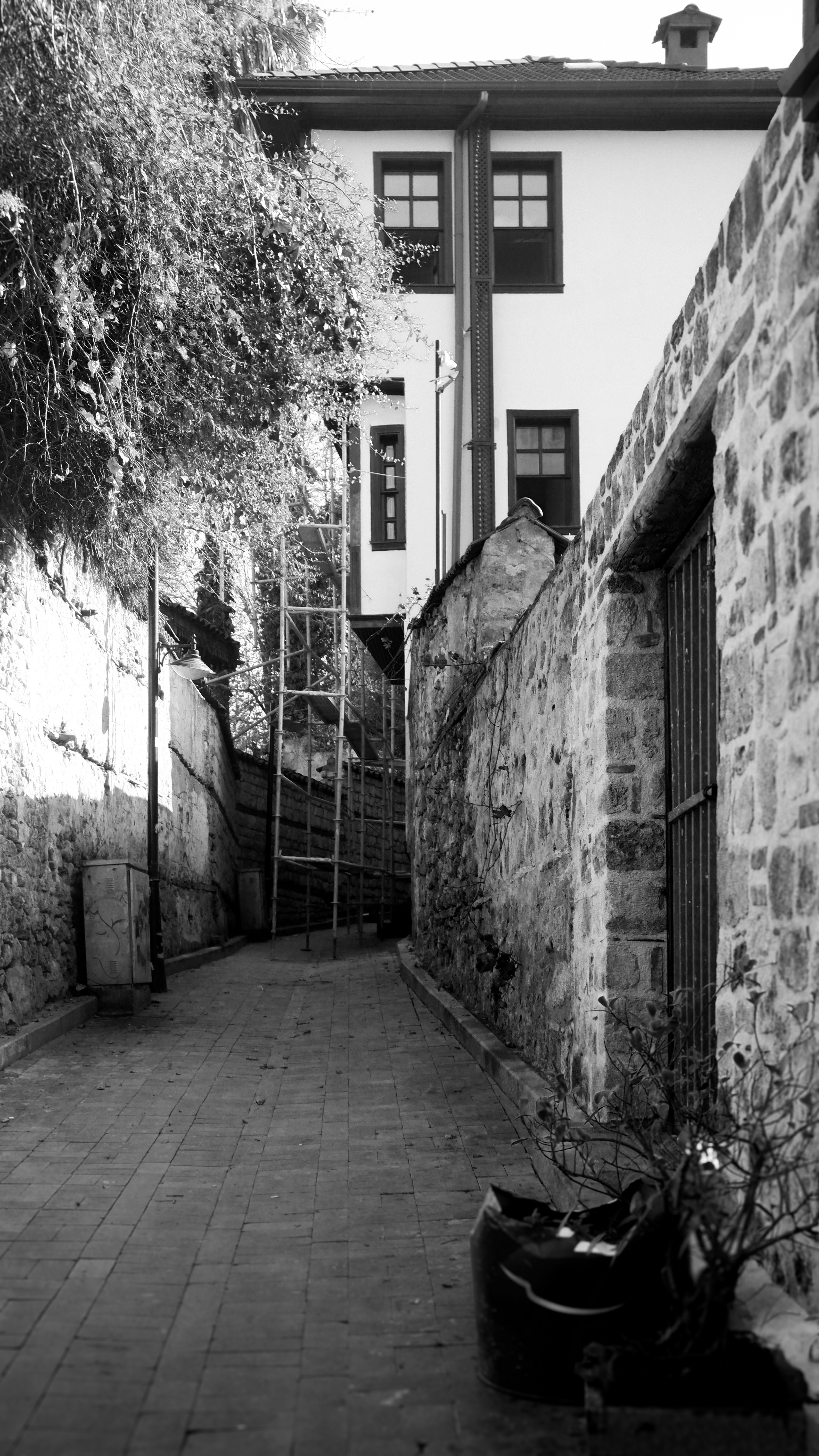 A scenic narrow alley with rustic stone walls leading to a historic building.
