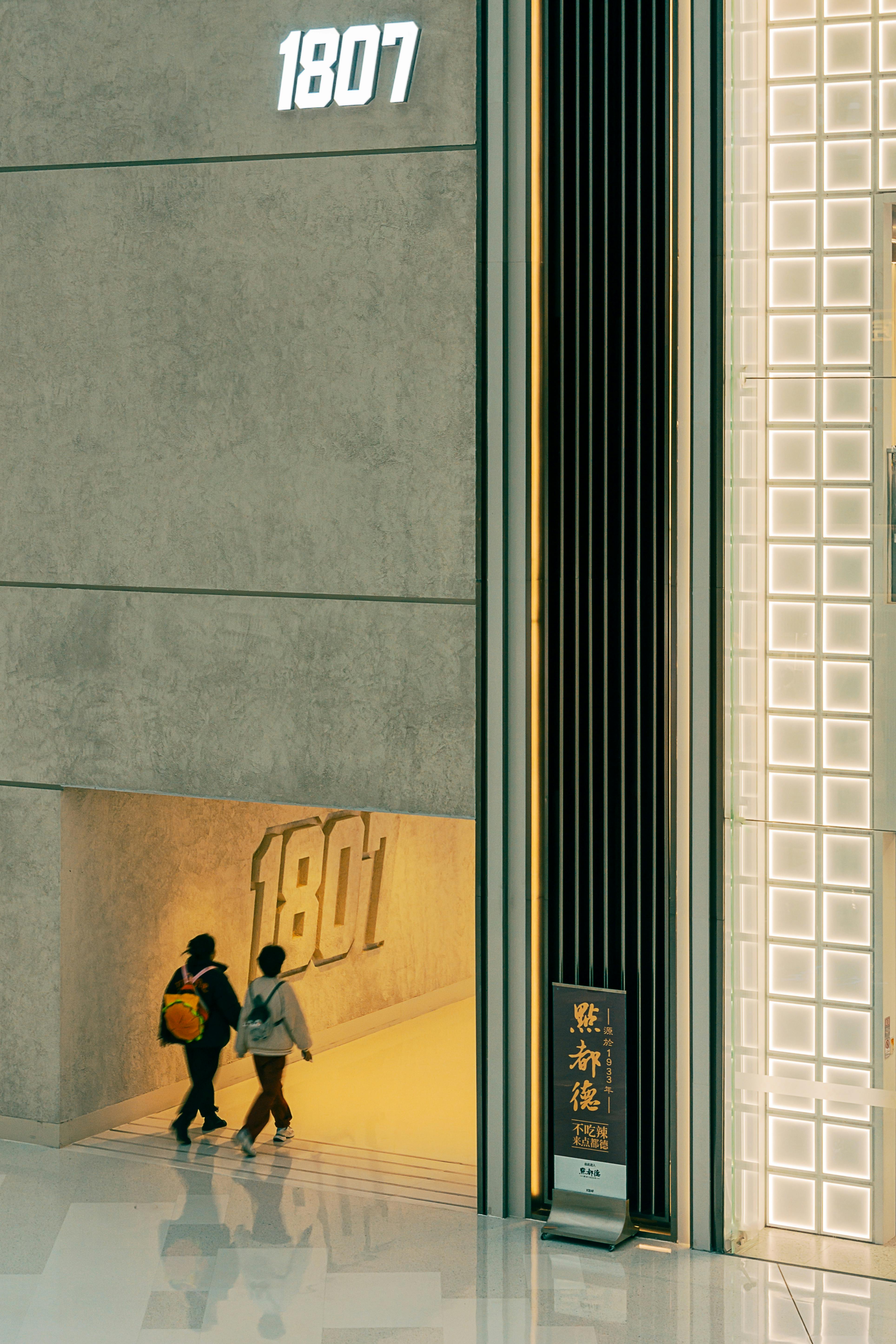 Two people walking through a modern building entrance labeled 1801.