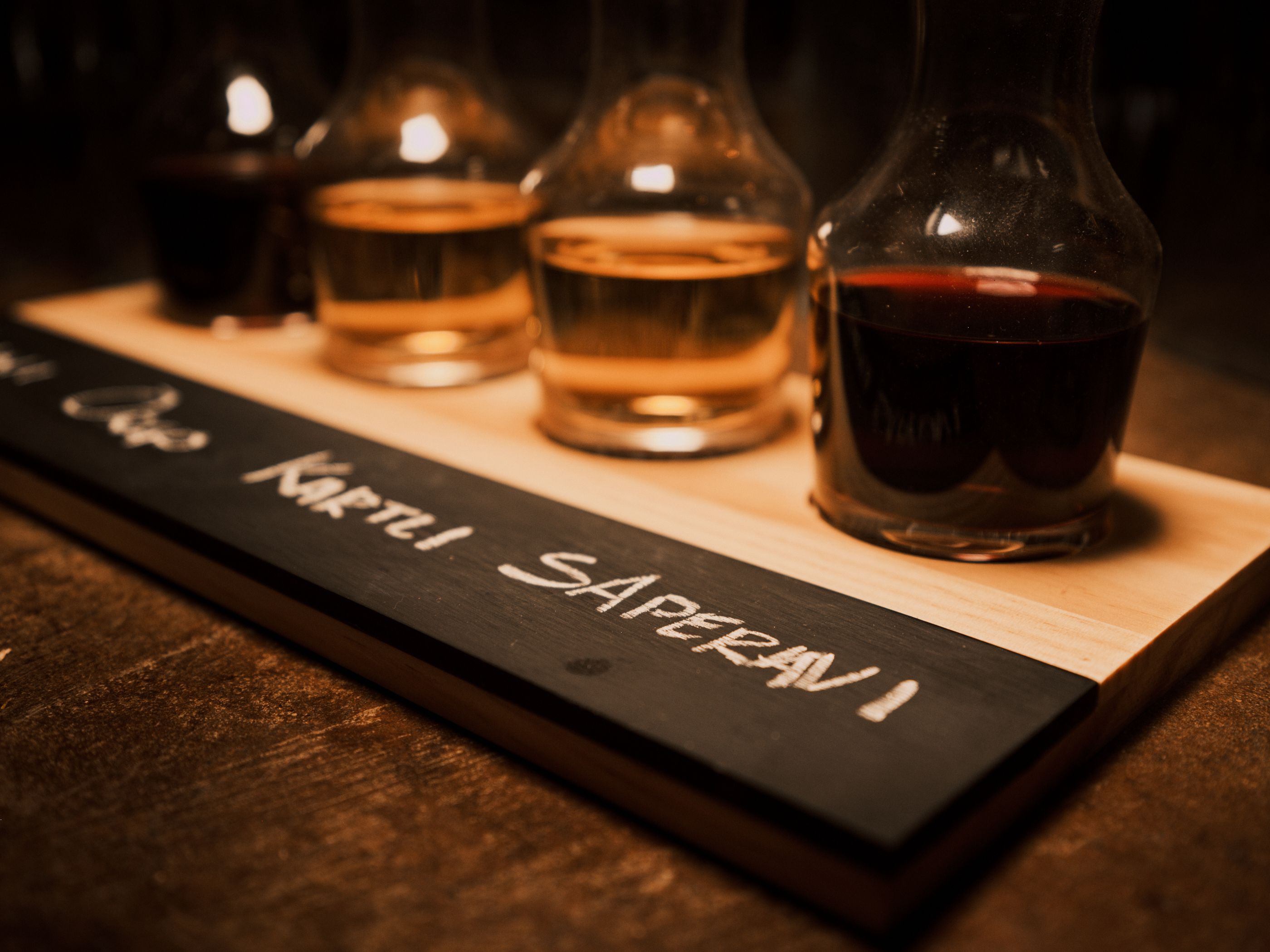 An artistic display of a wine flight with mini carafes labeled on a chalkboard tray, perfect for restaurant promotions. An artistic display of a wine flight with mini carafes labeled on a chalkboard tray, perfect for restaurant promotions.