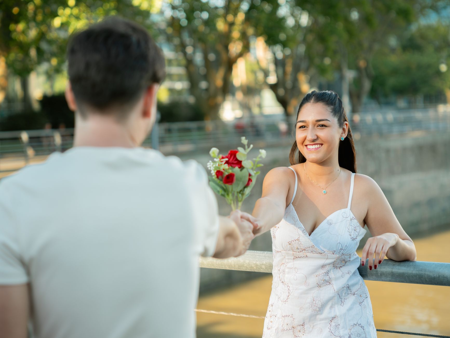 Young couple exchanging roses by the riverside in Buenos Aires, capturing a romantic moment.