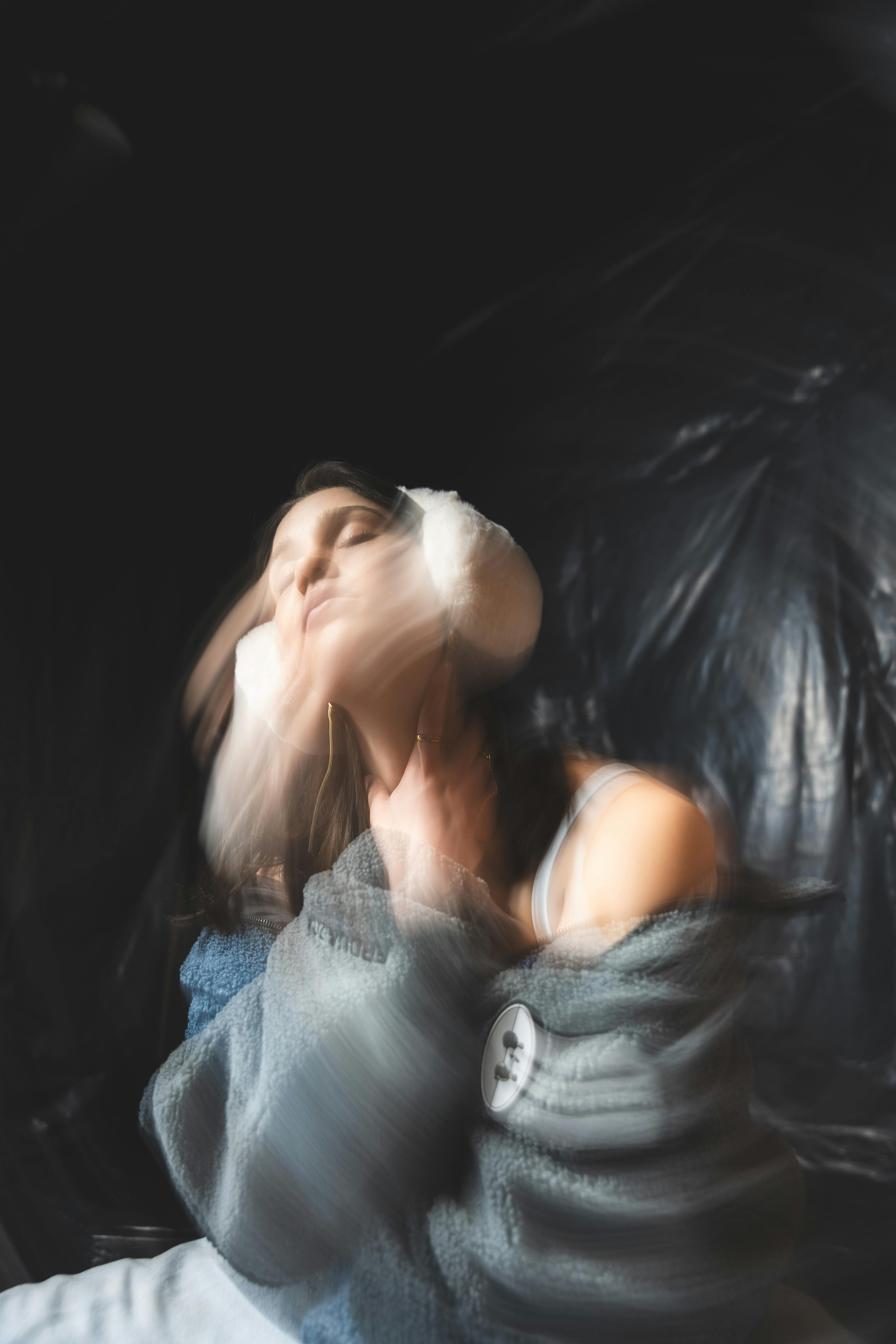 Creative blurred portrait of a Caucasian woman with yarn earmuffs, evoking a sense of motion.