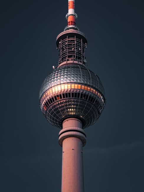 Close-up of the iconic Berlin TV Tower against a dark evening sky.