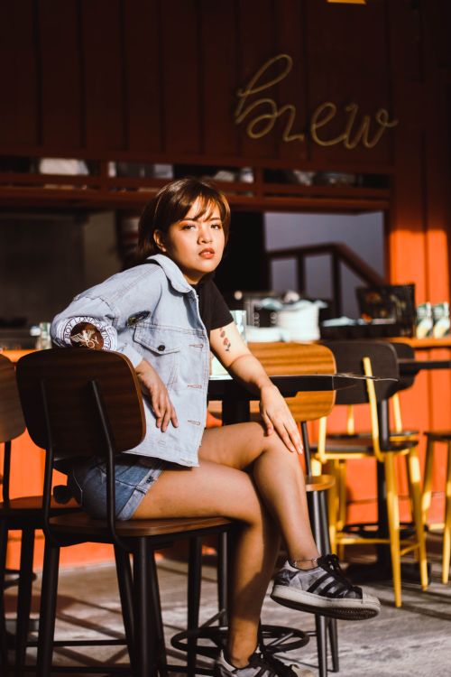 Free Stylish young woman in casual wear, enjoying leisure time in an urban coffee shop. Stock Photo