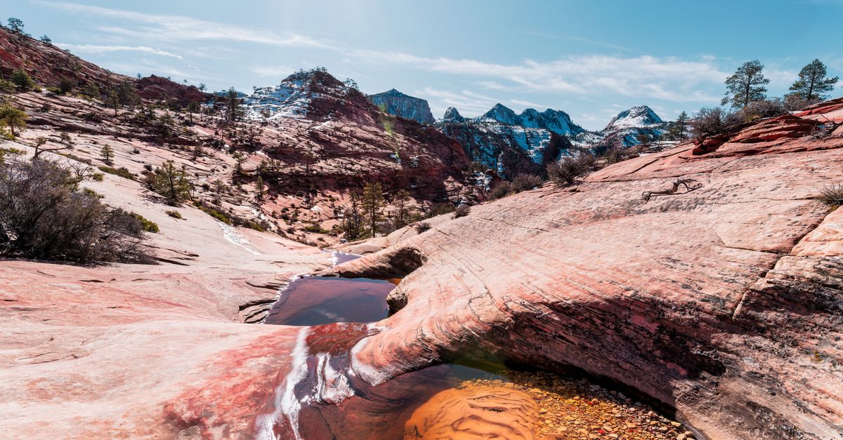 utah desert hot springs steaming, natural thermal pools rocky terrain, snow-capped mountains soaking, misty canyon pools morning