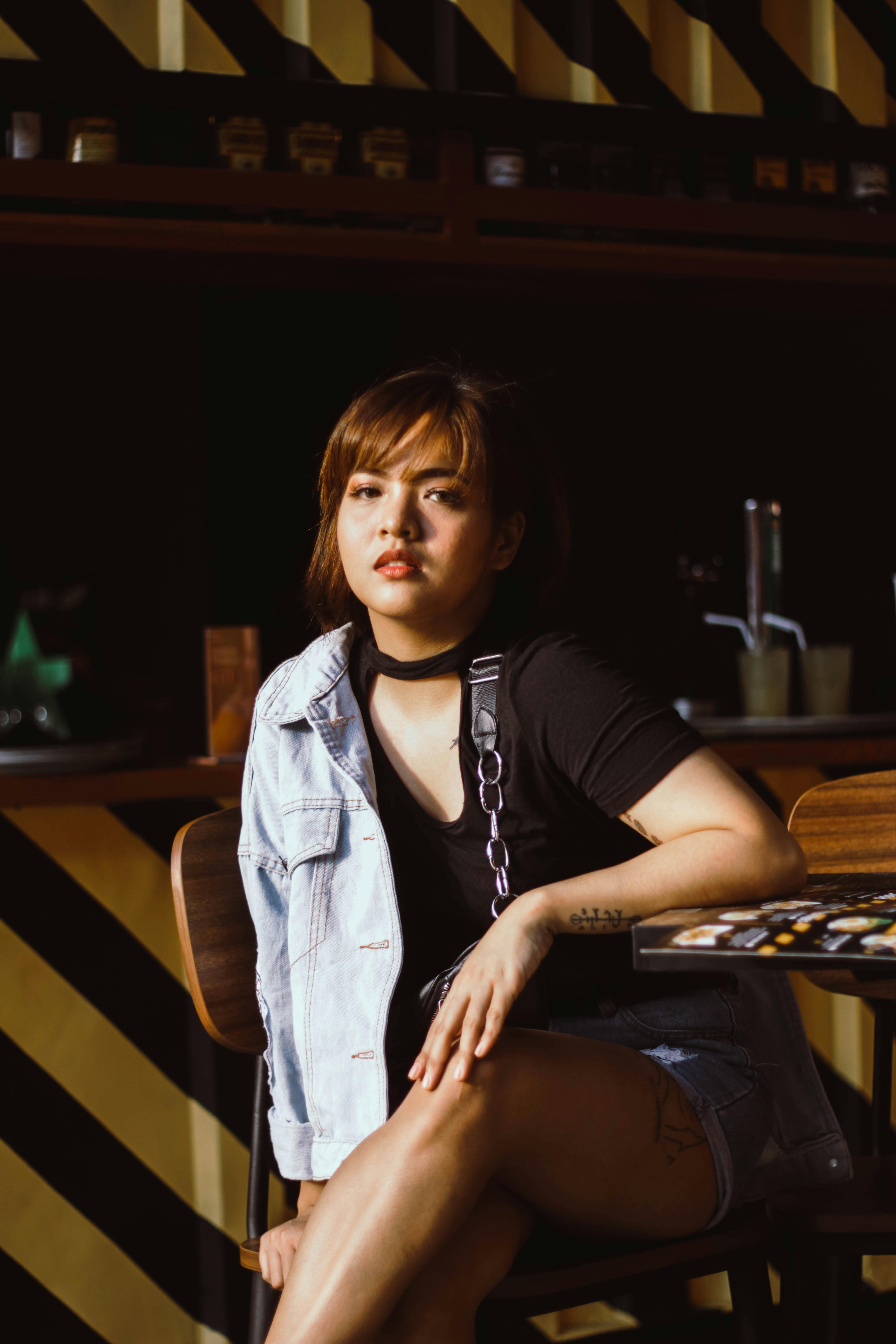A fashionable woman in casual attire enjoying a moment in a modern cafe setting.