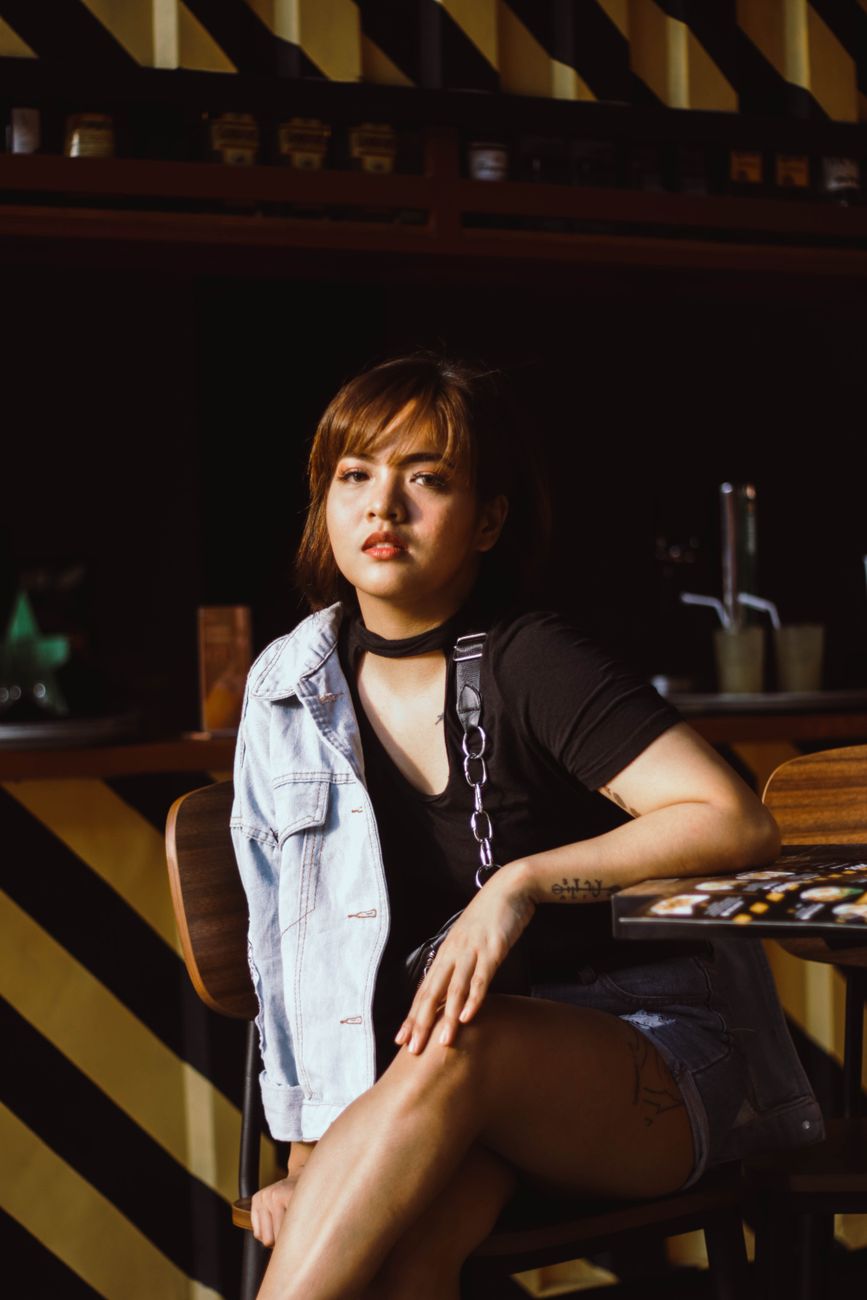 A fashionable woman in casual attire enjoying a moment in a modern cafe setting.