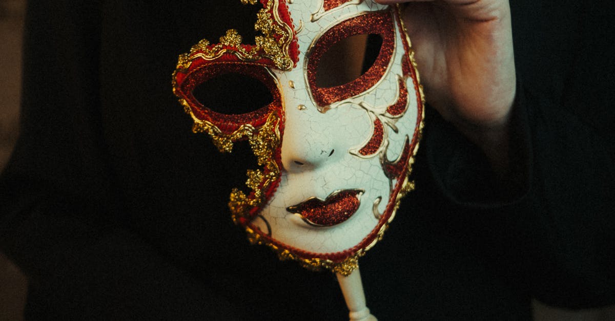 Close-up of an ornate venetian mask held by a woman in elegant attire.