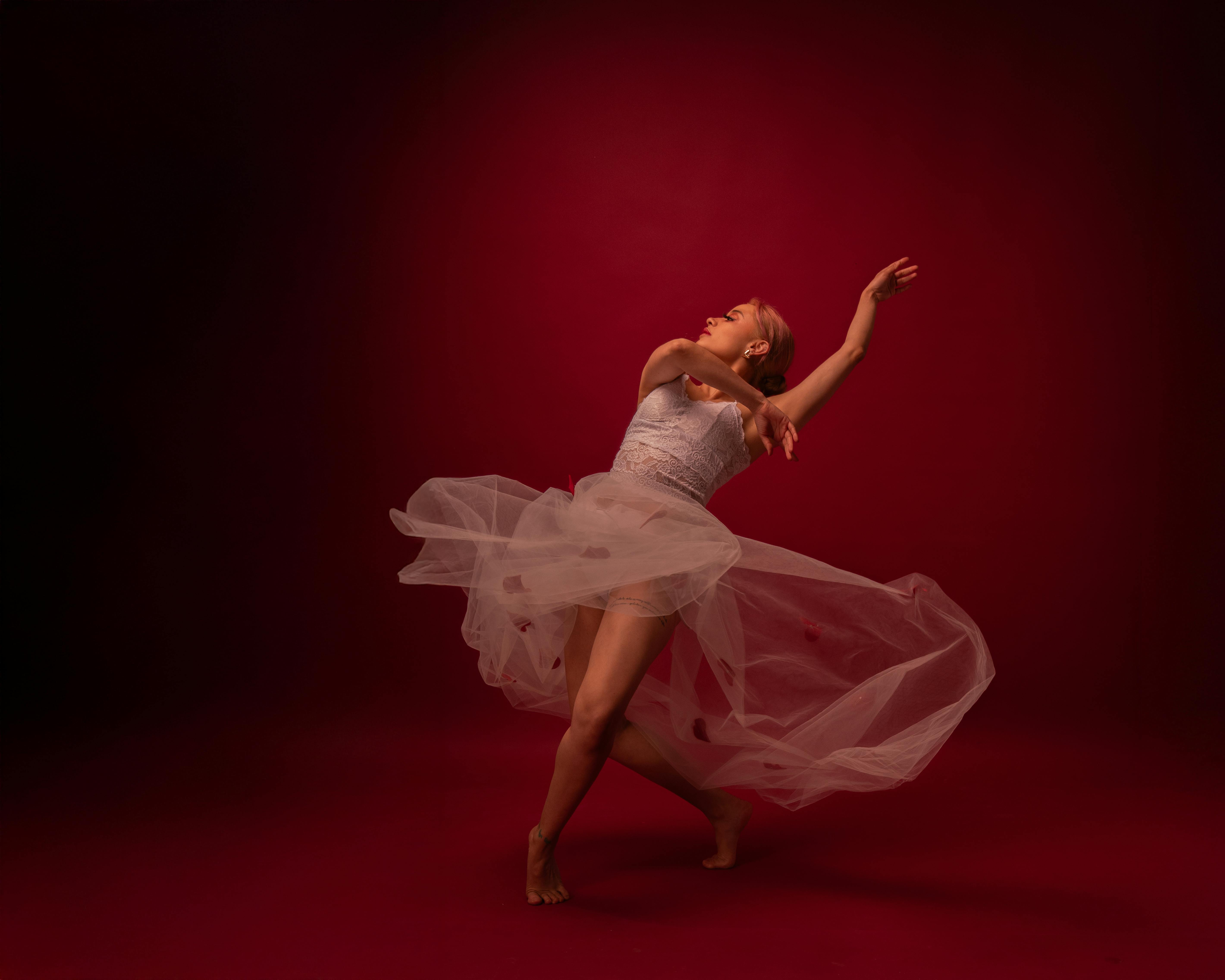 Ücretsiz Canlı kırmızı bir fon önünde poz veren zarif bale dansçısı hareket ve zarafeti sergiliyor. Stok Fotoğraflar