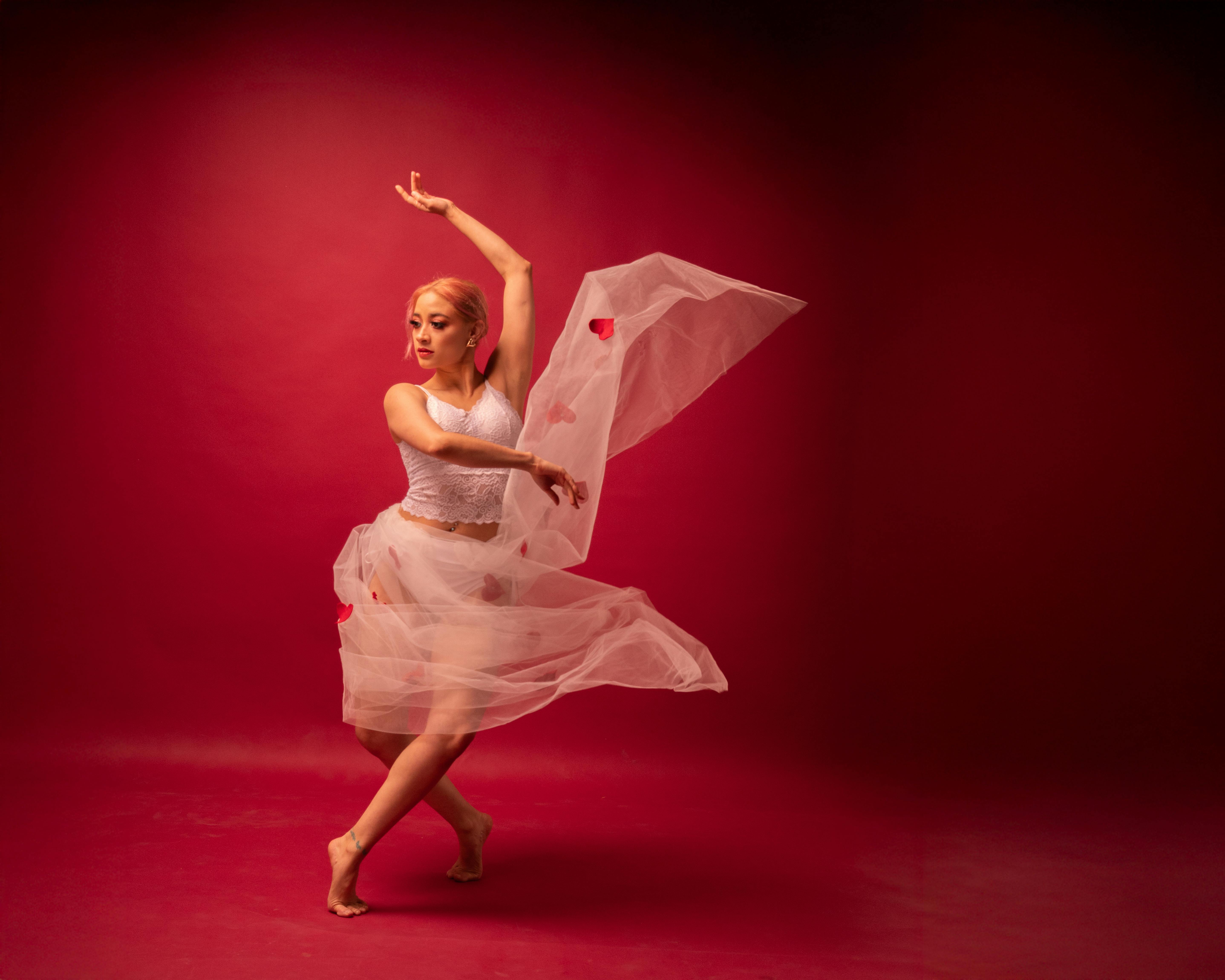 Ücretsiz Canlı kırmızı bir fon önünde zarafeti ve tutkuyu yansıtan zarif bale dansçısı. Stok Fotoğraflar