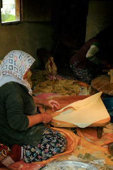 Women preparing traditional bread in an open kitchen setting, showcasing handmade dough preparation.