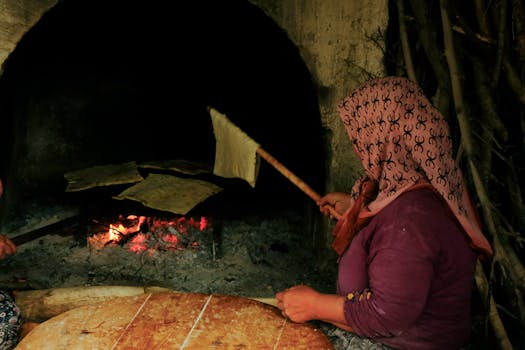 Rural woman baking flatbread in a rustic stone oven. Captures cultural heritage.
