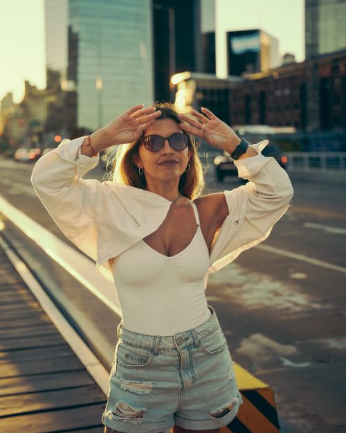 Free Stylish woman poses confidently in Buenos Aires cityscape with modern skyscrapers at sunset. Stock Photo