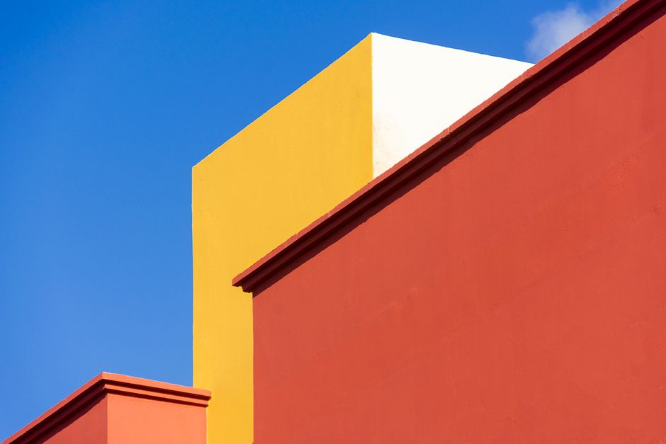 Vibrant abstract image of a building facade with geometric shapes against a blue sky.