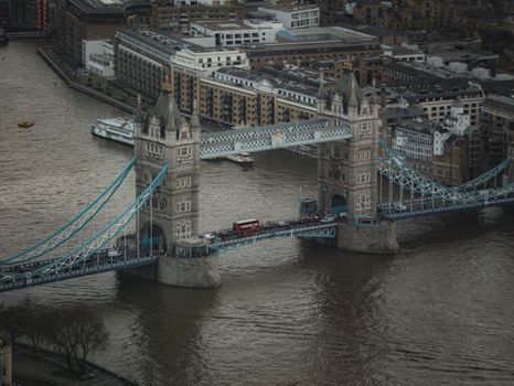 Aerial photo of Tower Bridge in London with a red bus crossing.