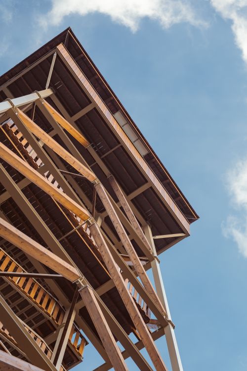 Free A view of a wooden lookout tower reaching into the blue sky in Muszyna, Poland. Stock Photo