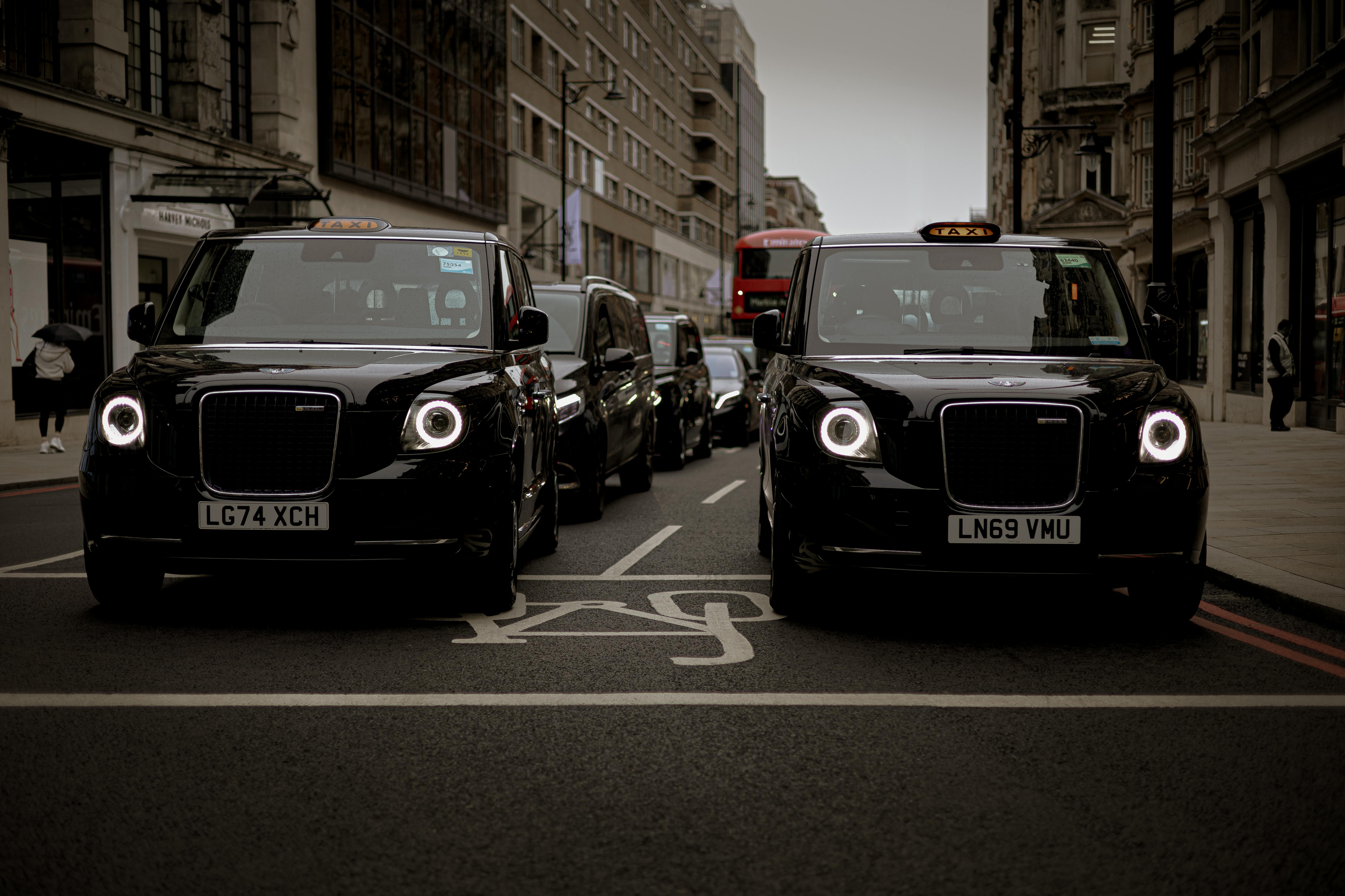 Black taxis line up on a London street showcasing modern urban transportation.
